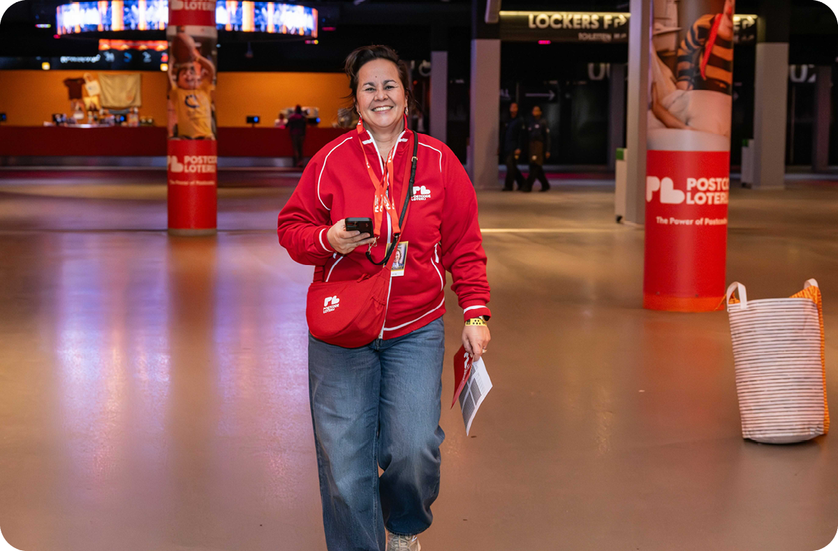Inge Kuin aan het werk in de ontvangsthal van Afas Live. Op de achtergrond reclamezuilen met Loterijposters.
