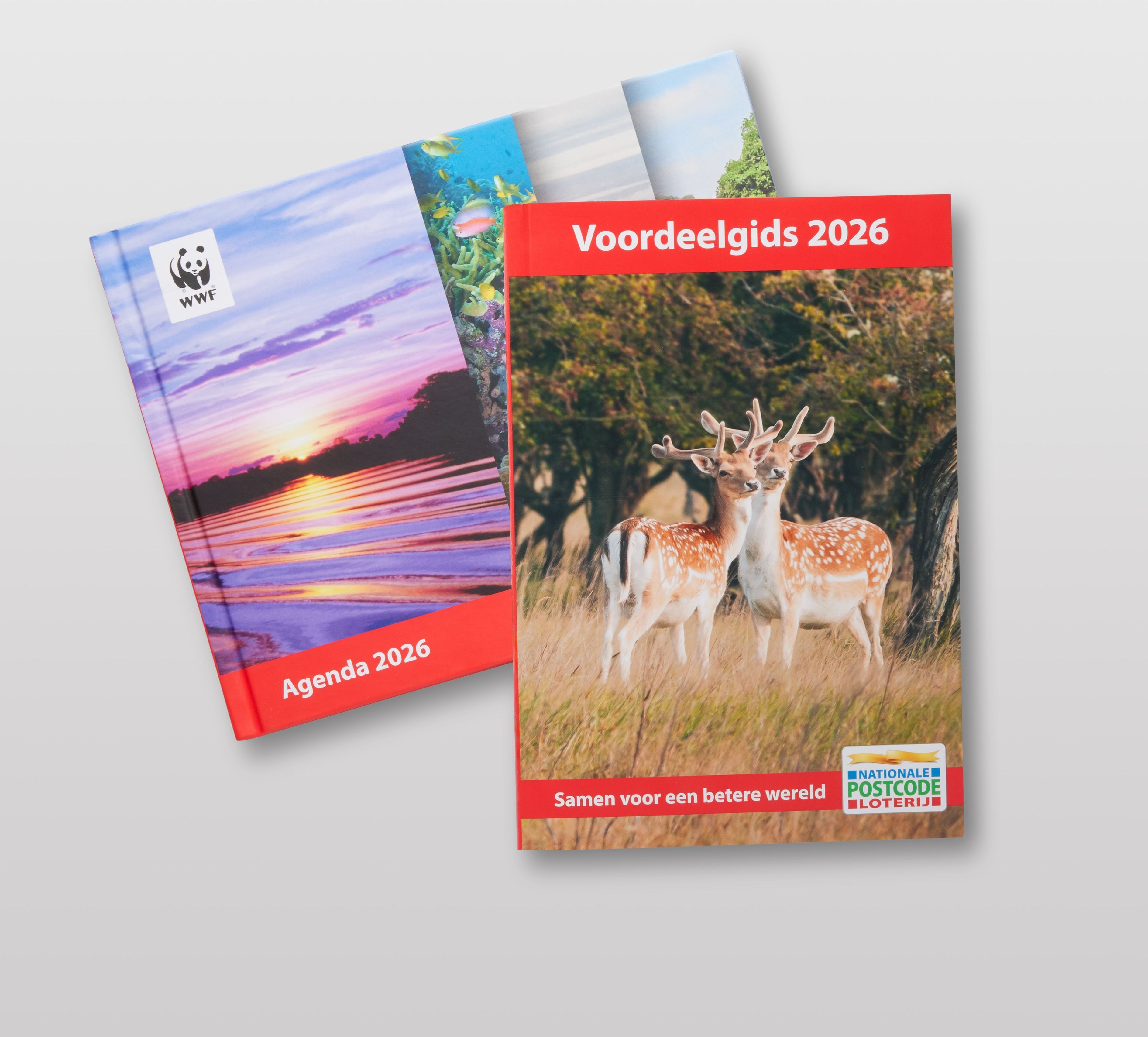 Een Wereld Natuur Fonds agenda met een zonsondergang en de tekst “Agenda 2026”. Daarbovenop ligt een boekje met de titel “Voordeelgids 2026” met een afbeelding van herten en het logo van de Postcode Loterij.